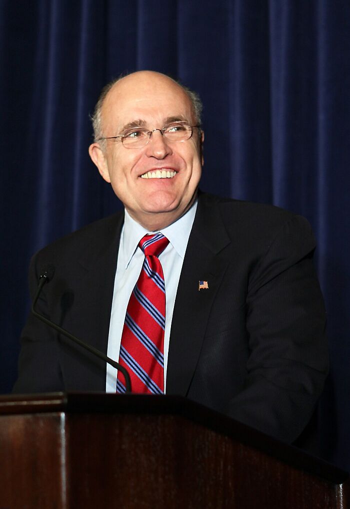 Rudy Giuliani, a public figure, smiling at a podium. Many public figures destroyed their own legacies.