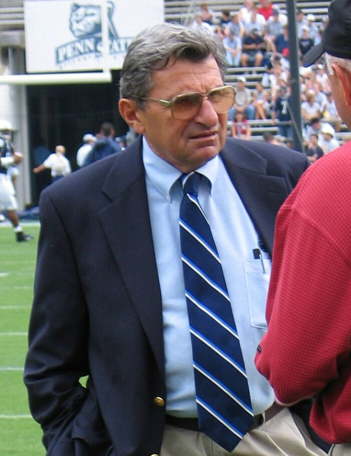 A public figure in a suit and tie on a sports field, destroying his legacy.