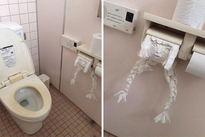 Toilet paper roll art with braided legs and a drawn face in bathroom