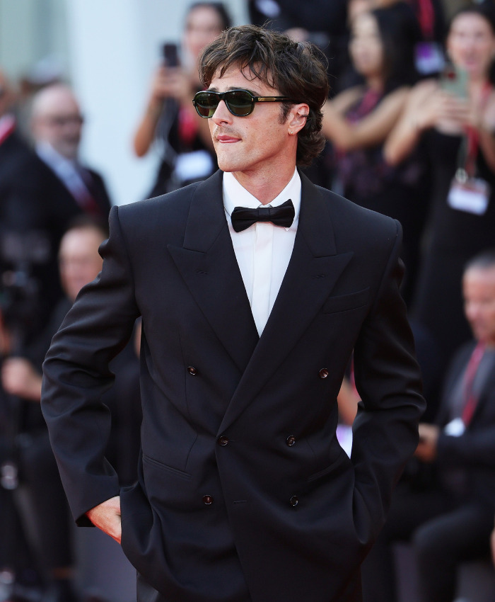 Jacob Elordi on the Venice Film Festival red carpet, wearing a tailored black suit and sunglasses. Jacob Elordi on the Venice Film Festival red carpet, wearing a tailored black suit and sunglasses.