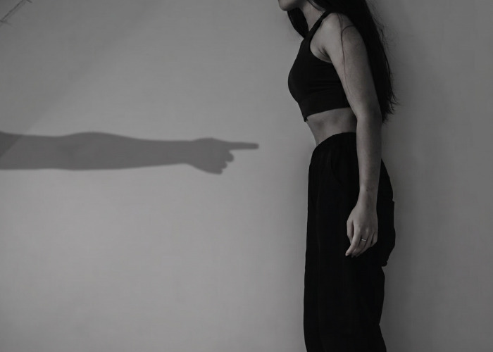 A person standing against a wall with a pointing shadow, representing the impact of a dangerous personality type. A person standing against a wall with a pointing shadow, representing the impact of a dangerous personality type.