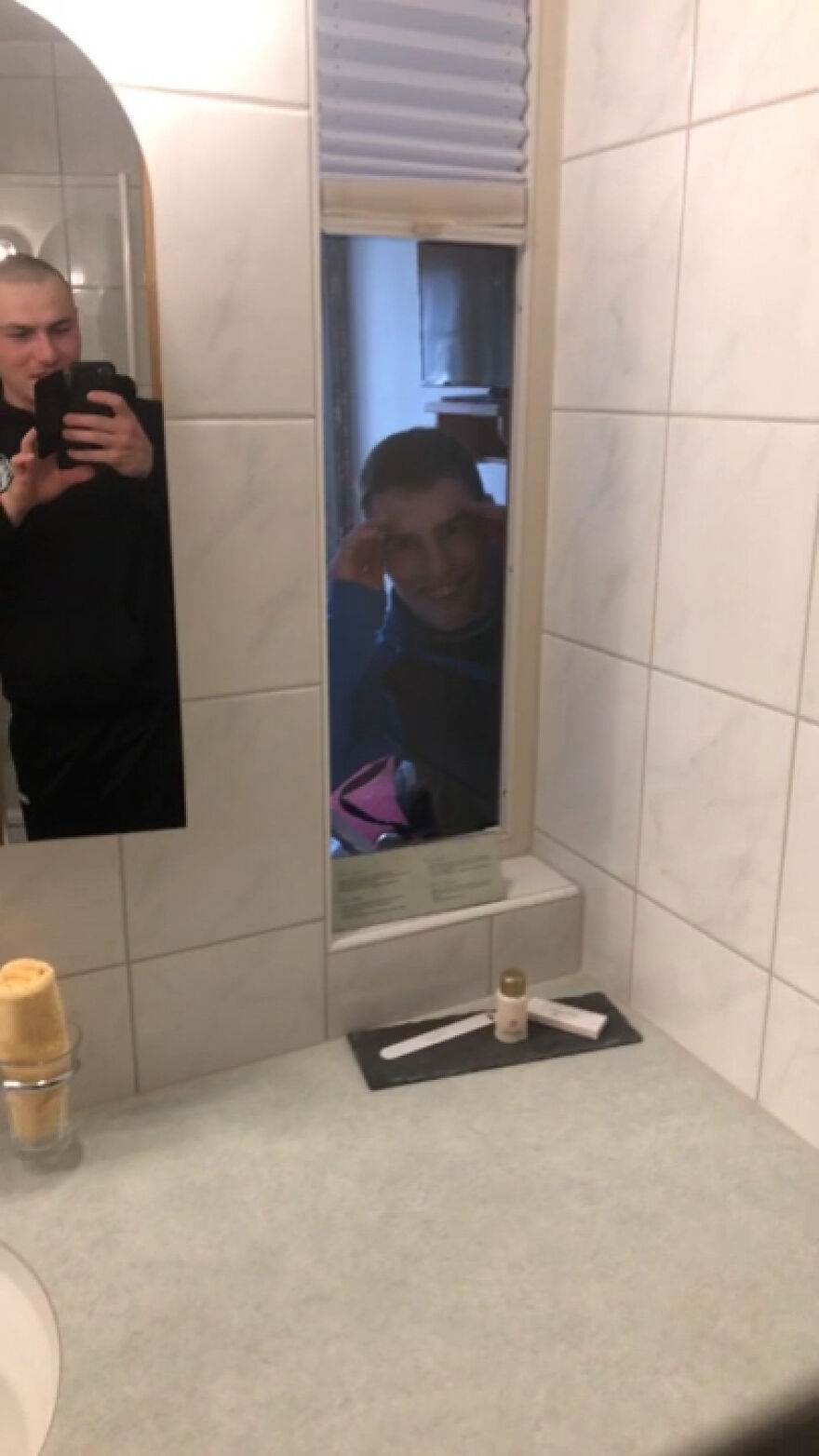 Bathroom mirrors reflecting two people in a hotel featuring unusual mirror placement