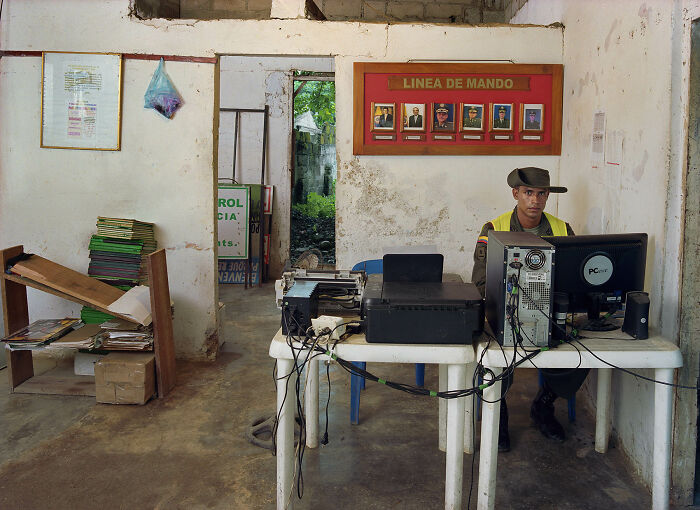 Photographer's project shows a man in a military uniform working on a computer in a simple office, depicting bureaucracy.