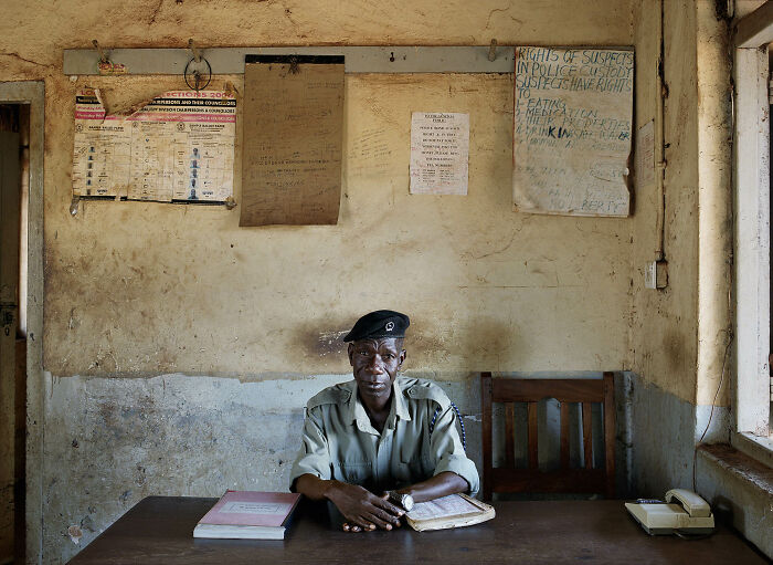 Photographer's project of an older man in a uniform sitting at a desk in a rustic bureaucratic office.