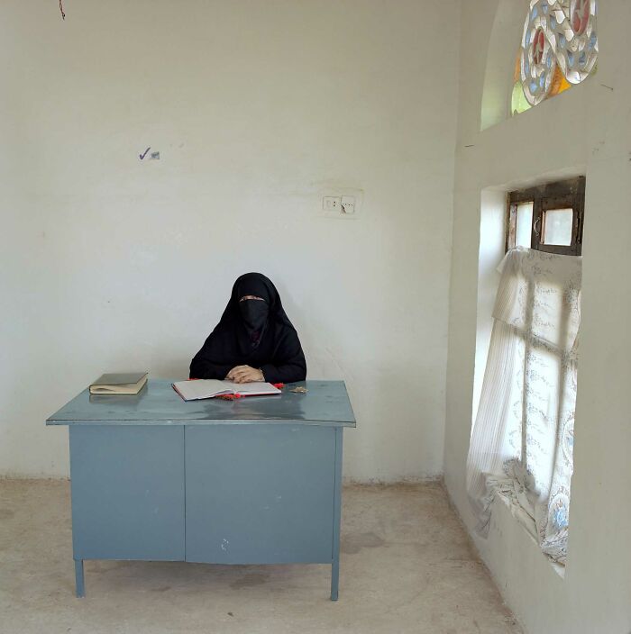 Photographer's project documents a woman in a black abaya sitting at a desk in a minimalist bureaucratic office.