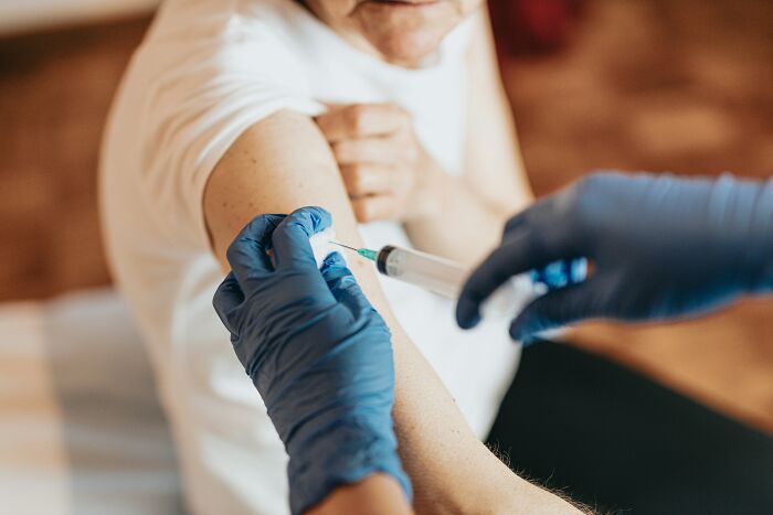 A doctor giving an injection to a patient's arm, illustrating standard medical procedures.