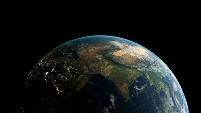View of Earth from space, showing continents lit by city lights and clouds, highlighting cool facts about the universe.