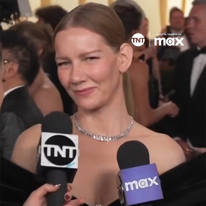 Actress on the red carpet with a mic, in a black off-shoulder dress, smiling during the Hollywood debate. Actress on the red carpet with a mic, in a black off-shoulder dress, smiling during the Hollywood debate.