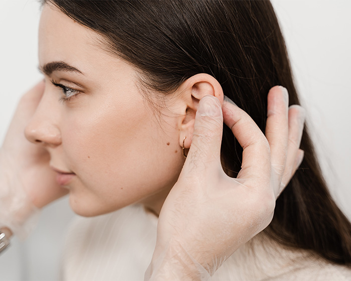 A close-up of a person's ear being examined, related to plastic surgery speculation.