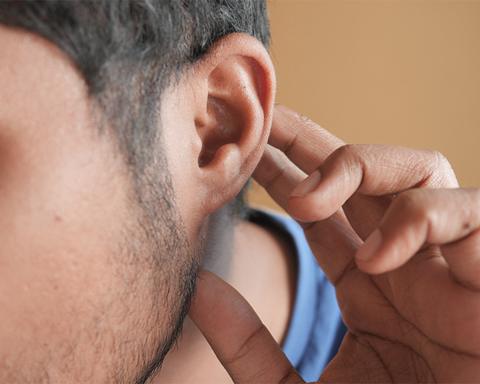 A close-up of a man's ear, touching it as plastic surgery speculation rises around Adam Driver.