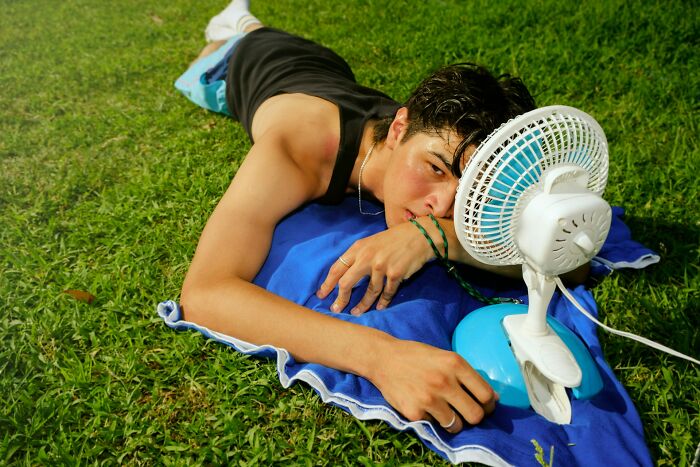 A person lying on grass with a fan nearby, symbolizing stupid things people said without realizing.
