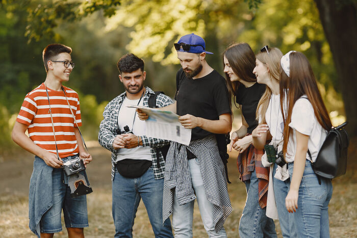 A group of friends looking at a map outdoors, enjoying their satisfying stories together.
