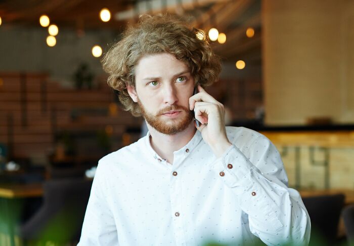 Man in white shirt talking on phone in restaurant setting