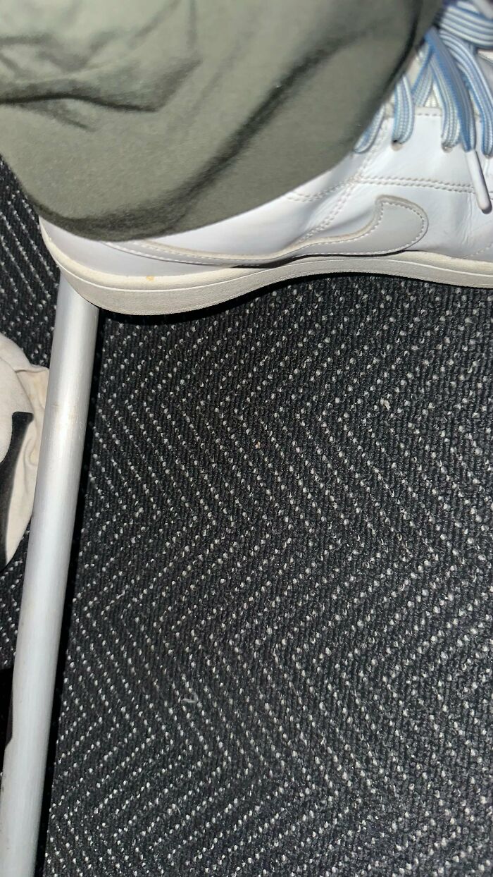 A woman's feet are seen under an airplane seat, showing where an entitled man kicked her.
