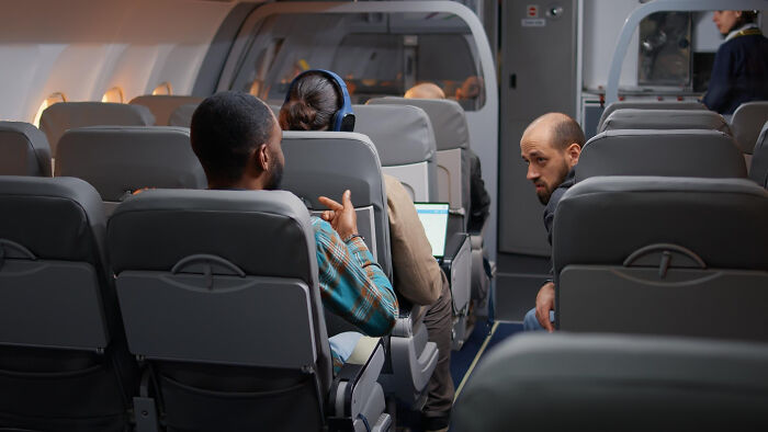 An entitled man kicking under a woman's seat on an airplane.