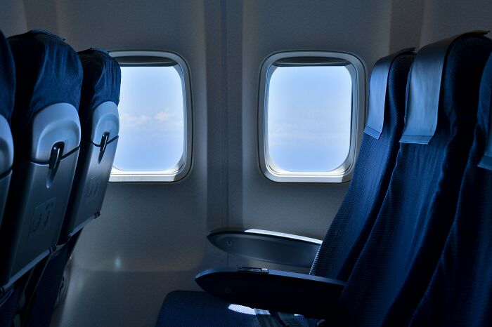 Empty airline seats beside two windows, showcasing the view from an airplane.