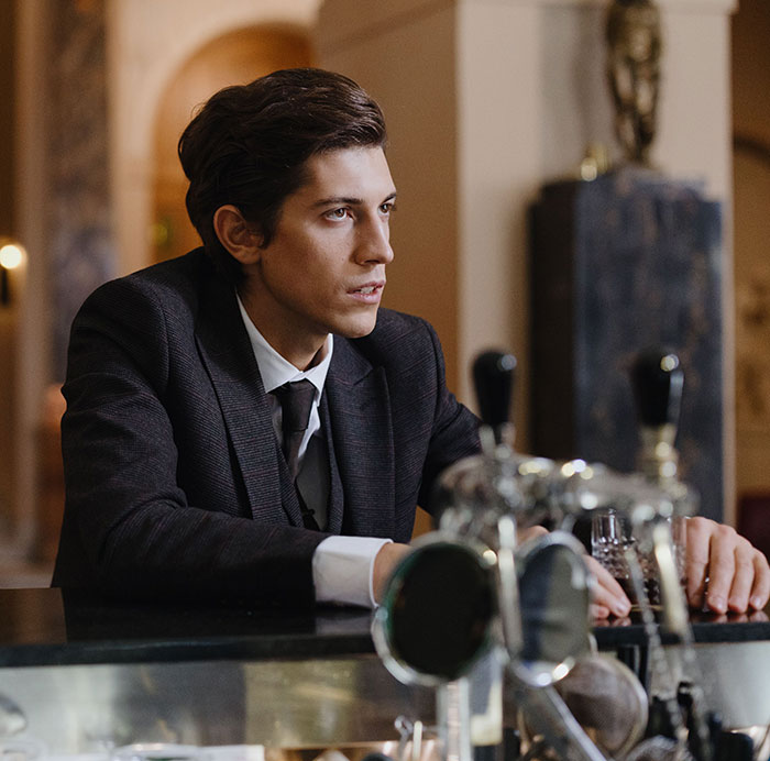 Young man in suit sitting at bar contemplating drinking problem Young man in suit sitting at bar contemplating drinking problem