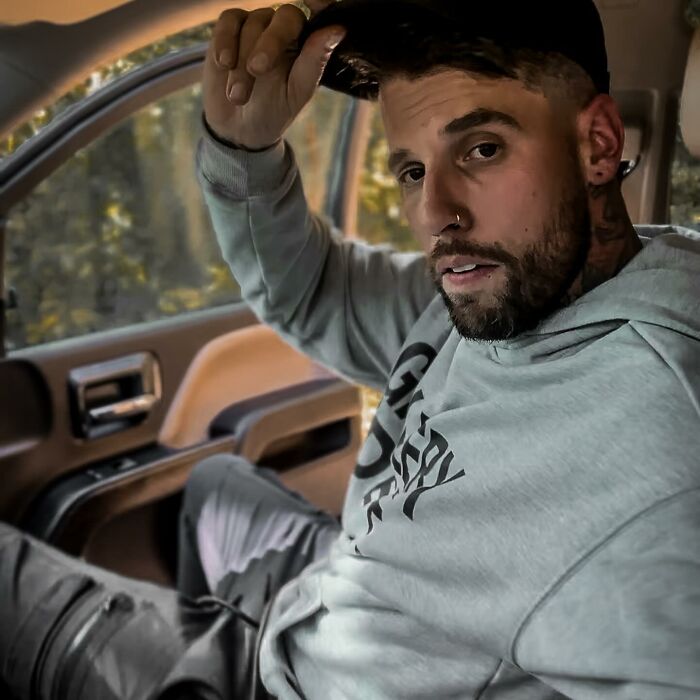 Man in casual hoodie and cap in car showcasing reflection on drinking problem Man in casual hoodie and cap in car showcasing reflection on drinking problem