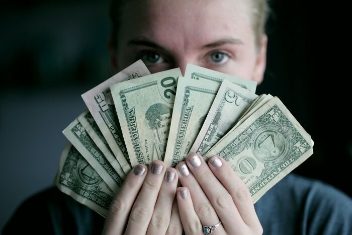 A person holding a fan of money, reflecting on the financial implications of going no contact with a parent.