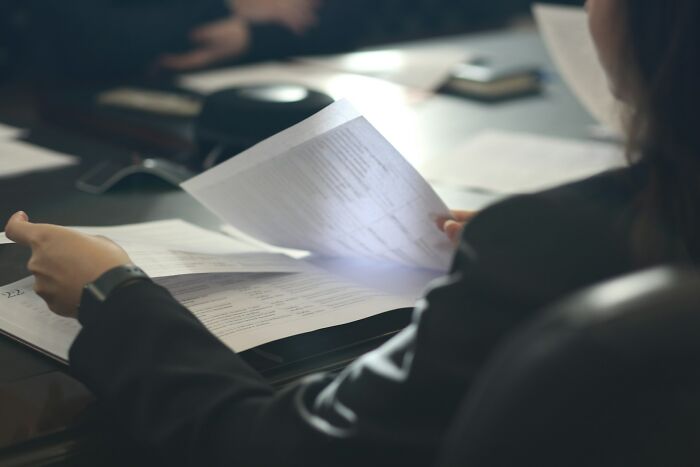 An individual in a business suit reviewing document pages in a meeting, related to ridiculous arguments in court.