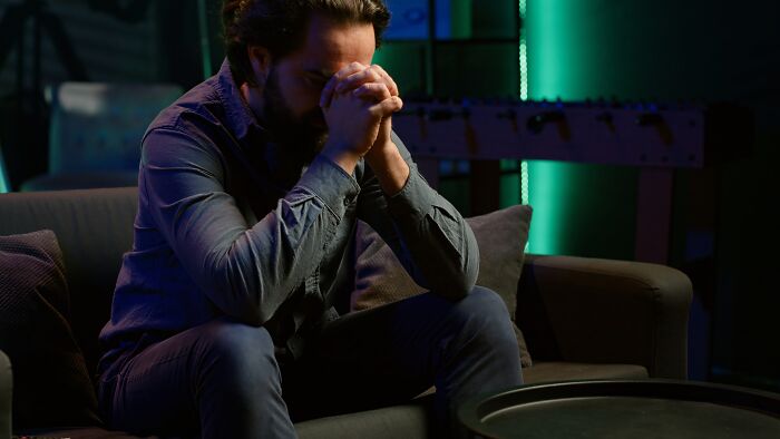 A man sitting with his head in his hands, depicting the regret and thoughts men have regarding their divorce.