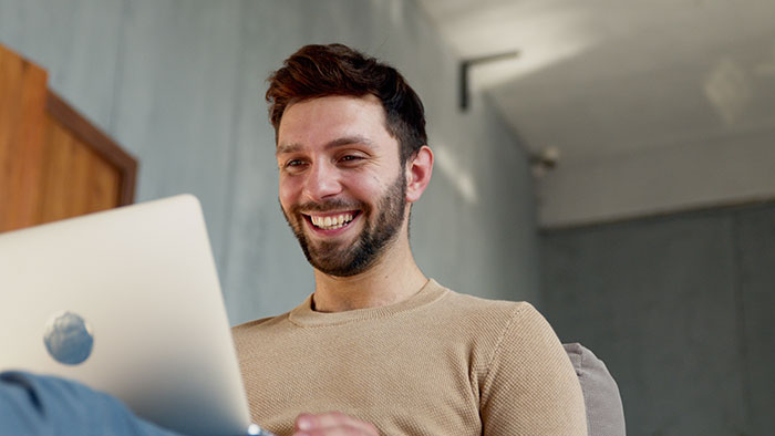 Happy photographer smiling at his laptop, delivering stunning family photos with a hidden detail and his epic revenge. Happy photographer smiling at his laptop, delivering stunning family photos with a hidden detail and his epic revenge.