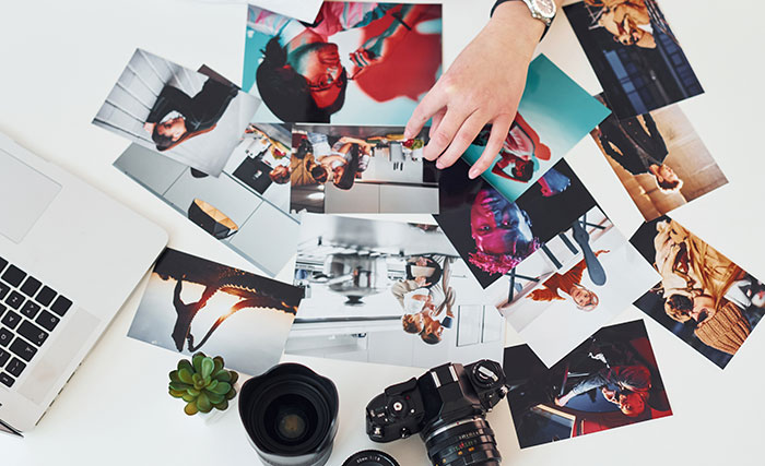 Overhead view of a photographer reviewing family photos, with a camera and lens on the table. Overhead view of a photographer reviewing family photos, with a camera and lens on the table.