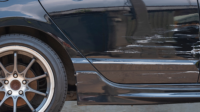 A black car with prominent key scratches on the side door and fender, leading to Karen losing a lawsuit.