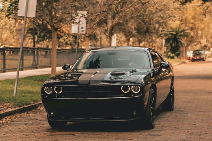 A black car, possibly a Dodge Challenger, parked on a street; a dumb Karen loses a lawsuit about a keyed car.
