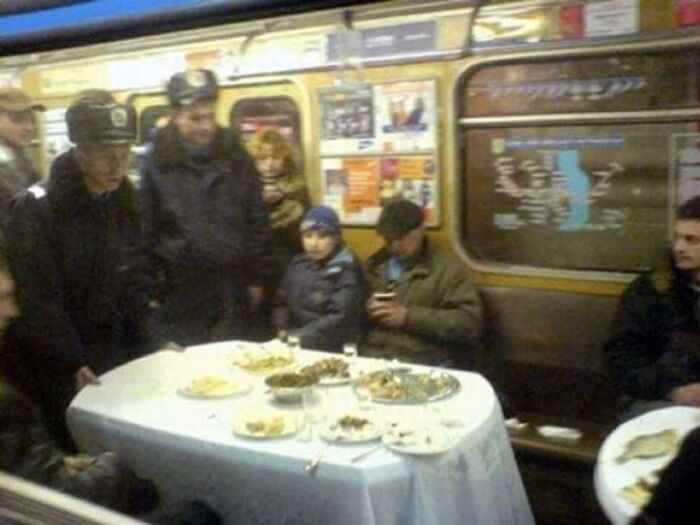 Passengers setting up a dinner table inside a subway car, a bizarre public transport interaction.