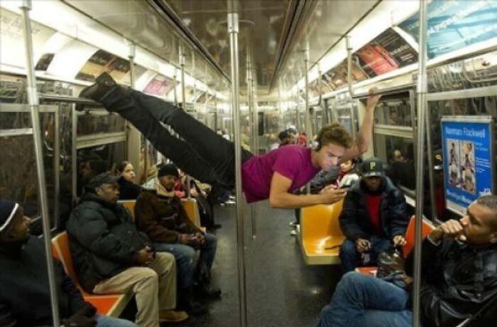 A man performing a flag pole pose on a subway train, illustrating wild public transport interactions.