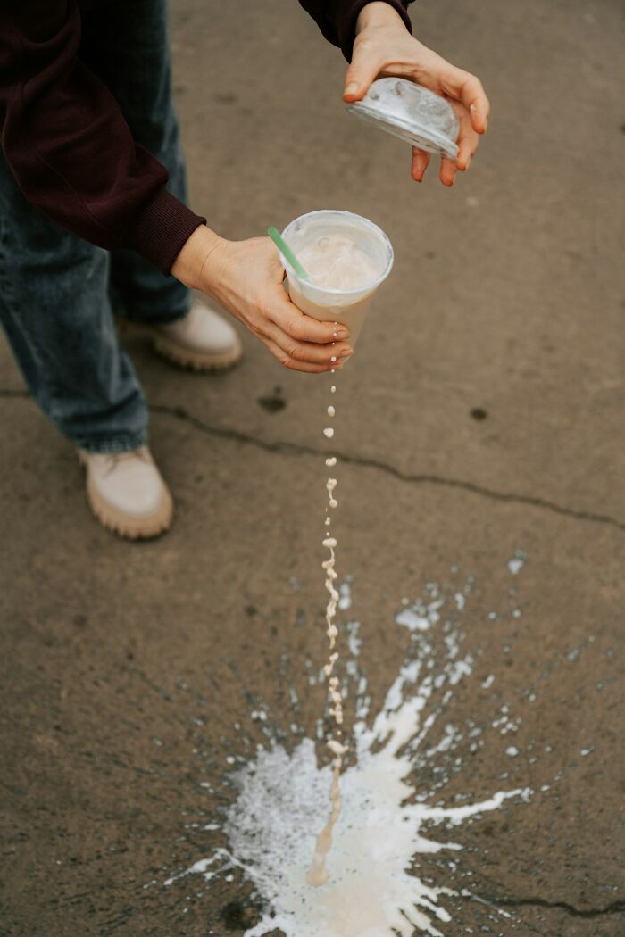 Hands spilling a drink on the ground, a common everyday inconvenience.