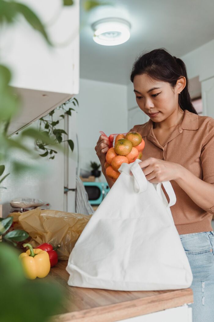 A young woman unpacking groceries, illustrating an everyday inconvenience of getting home and sorting out items.