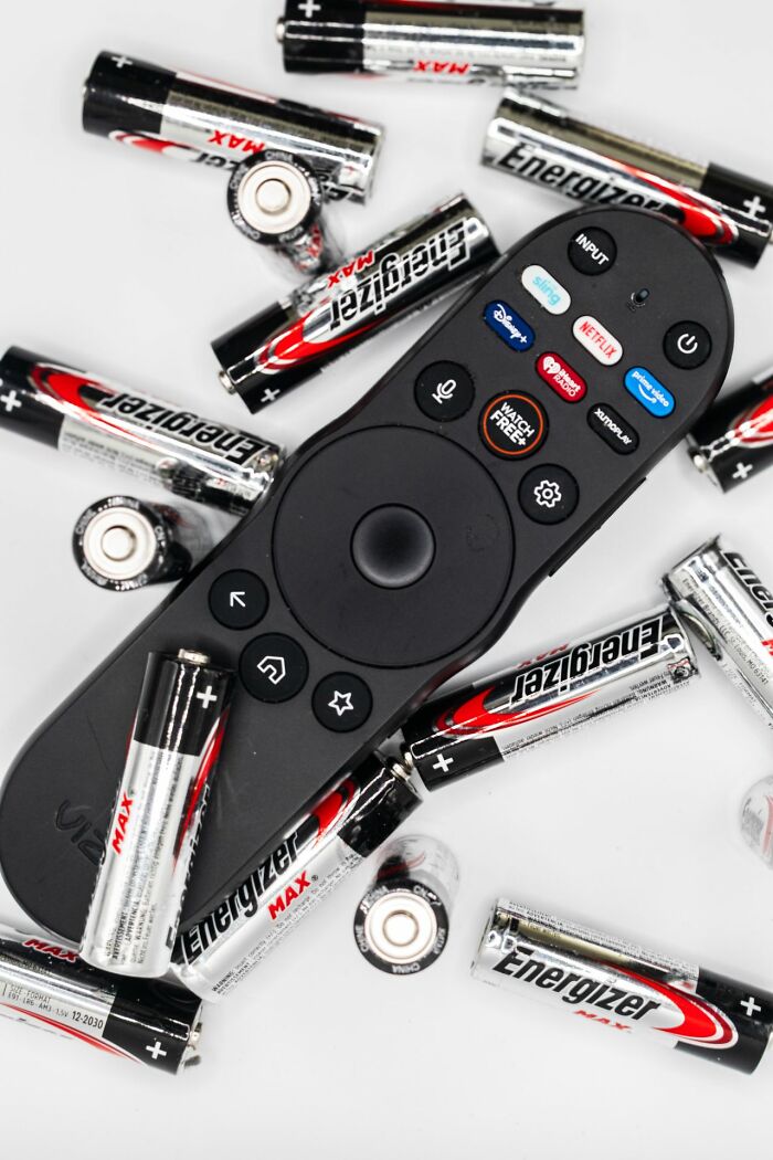 A TV remote surrounded by batteries, an everyday inconvenience when batteries run out.