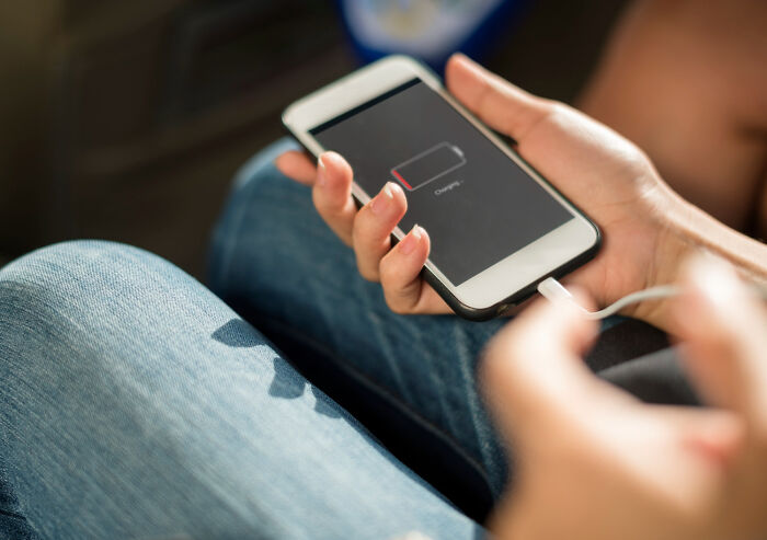 A person charges a smartphone with a low battery, an everyday inconvenience.