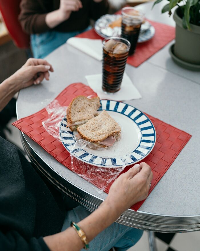 A sandwich still wrapped in plastic, an everyday inconvenience, sits on a table.