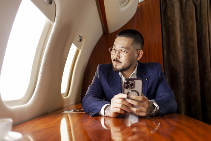 A man on a private jet looks out the window, highlighting surprising things wealthy people buy.