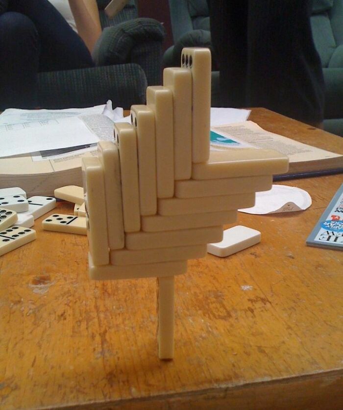 A baffling image of dominoes stacked in an impossible, free-standing structure on a wooden table.