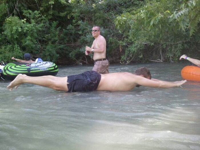 A baffling image of a man floating impossibly flat on river water, with other people on tubes in the background.