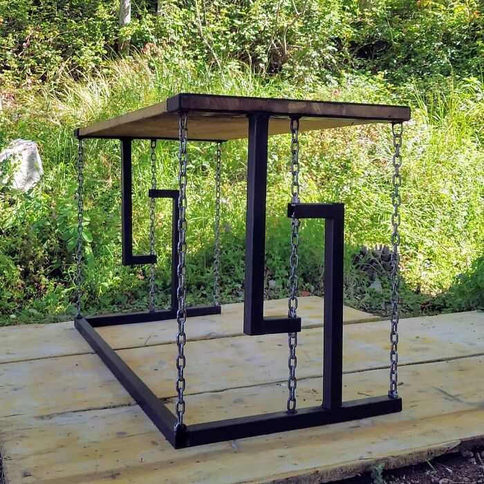 A wooden table with metal frame and chains, appearing to float, a baffling image that defies physical sense.