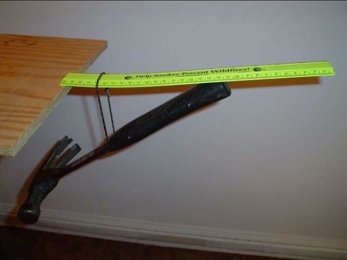 A hammer suspended by a string and ruler, demonstrating a baffling physical sense defying setup.