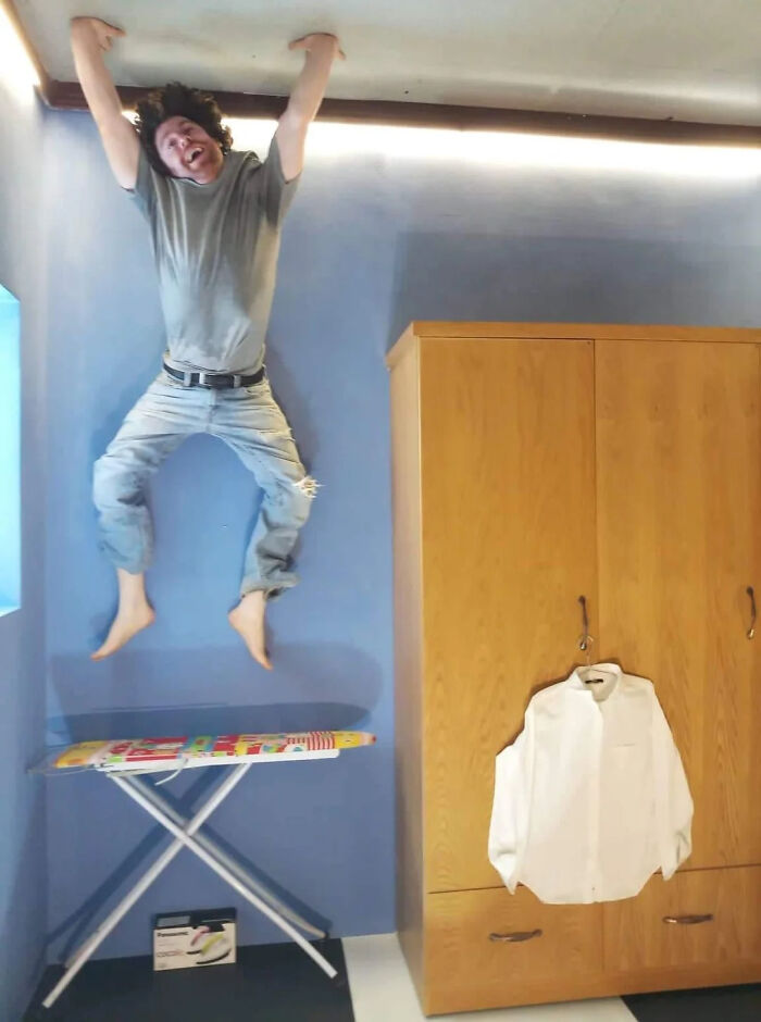 A man appearing to hang upside down from the ceiling in a room, one of the baffling images that make no physical sense.