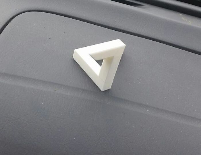 A small white Penrose triangle, an impossible object that creates a baffling image of perpetual ascent.