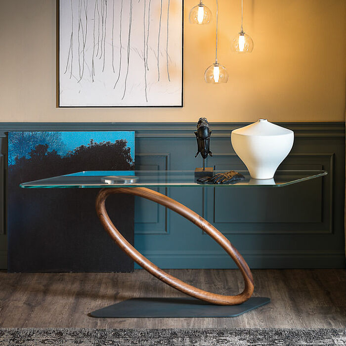 A modern glass table with a curved wooden base, creating a baffling image of a floating tabletop.