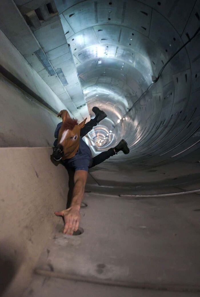 A baffling image of a person in a horse mask seemingly crawling out of a tunnel, defying physical sense.