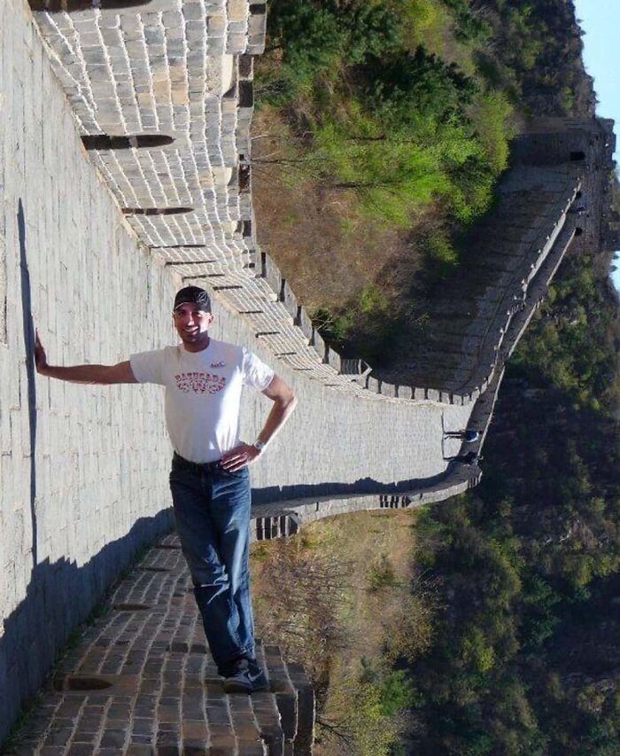 A baffling image of a man appearing to lean horizontally on the Great Wall of China, defying physical sense.
