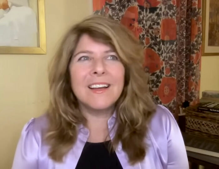 A public figure with long hair and a light purple shirt, smiling, destroying her legacy.