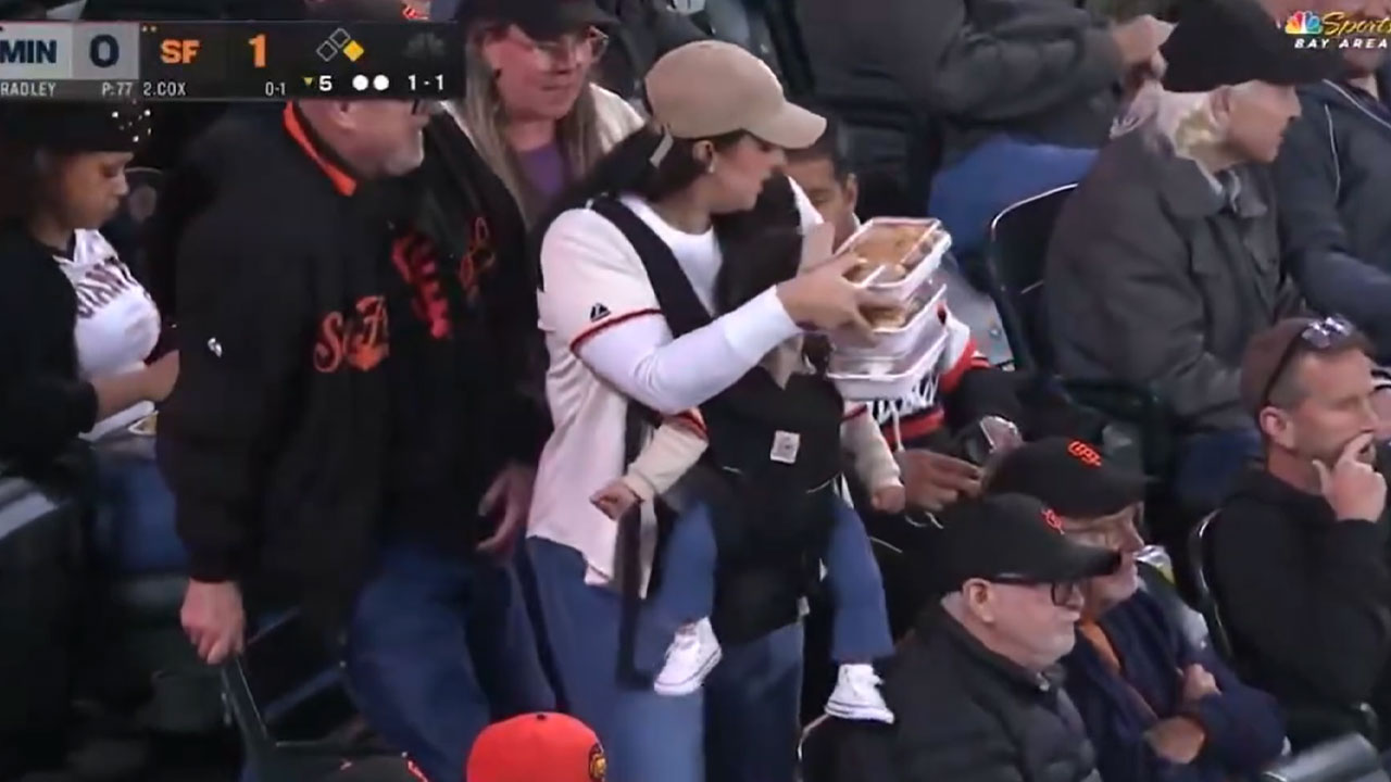 Giants Camera Catches Mom Doing Double Duty With A Baby And Food, Her Husband Just Gets Comfy