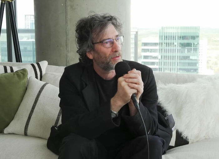 Neil Gaiman, a public figure, speaks into a microphone, reflecting on his legacy.