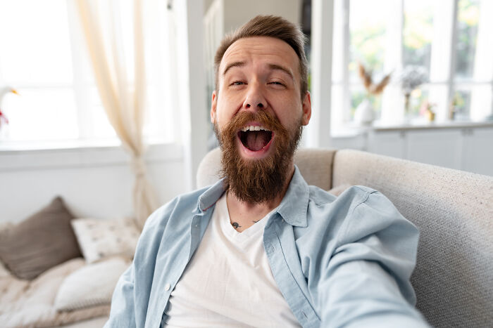 A laughing man with a beard, raising awareness about subtle sexism in social situations.